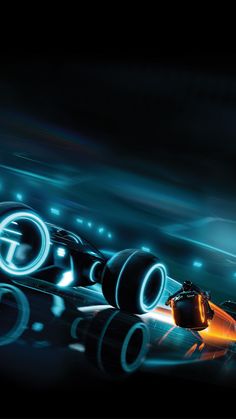 an orange and black race car driving on a track with lights coming from behind it