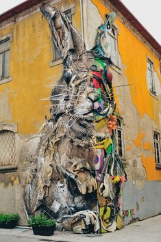 a large animal statue sitting in front of a building with graffiti on it's side