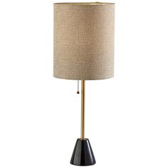 a black and gold table lamp with a beige shade on the top, sitting against a white background