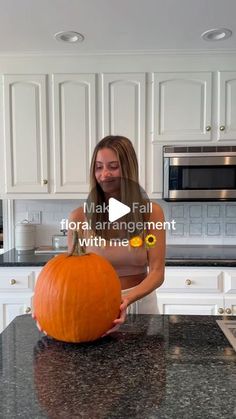 a woman is carving a pumpkin in the kitchen