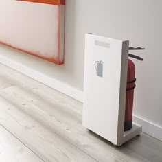 a white box sitting on the floor next to a red chair in front of a painting