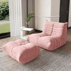 a pink chair and ottoman sitting on top of a rug in front of a window