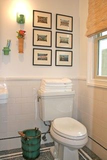 a white toilet sitting in a bathroom next to a window with pictures on the wall