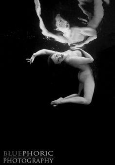 a black and white photo of a woman floating in the water