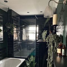 a bathroom with black tile walls and flooring has a bathtub, sink, and mirror