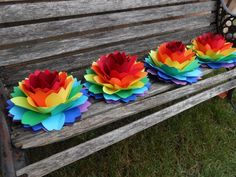 three paper flowers sitting on top of a wooden bench