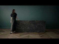 a woman is standing in front of a black marble counter with her hands on the wall