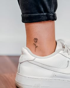 a woman's foot with a small rose tattoo on her left side ribcage