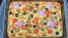 a square pizza with olives, onions and peppers in a metal pan on a table