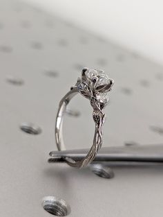 a diamond ring sitting on top of a piece of metal with holes in the background