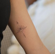 a woman's arm with a tattoo that has a dandelion on it