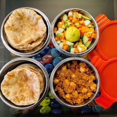 four tins filled with different types of food sitting on top of a glass table