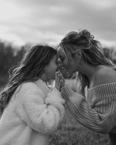 two women standing next to each other in a field