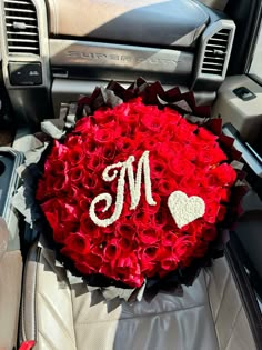 a bouquet of red roses in the front seat of a car with a monogrammed m on it