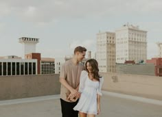 a man and woman are walking together on the roof in front of some tall buildings