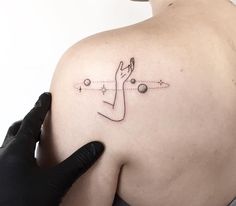 a woman with a tattoo on her shoulder is touching the back of her left shoulder