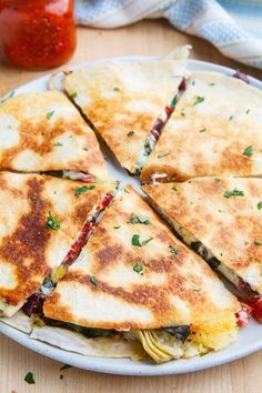 several quesadillas cut in half on a white plate with ketchup