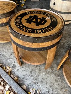 three wooden barrels sitting next to each other on top of a cement floor covered in leaves