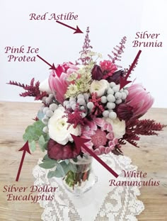 a vase filled with lots of flowers on top of a wooden table next to a lace doily