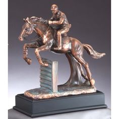 a bronze statue of a jockey on a horse jumping over a hurdle with his leg in the air