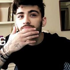 a man with tattoos on his arm sitting in front of a computer desk and looking at the camera