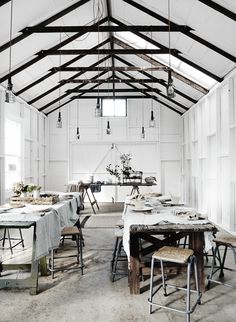 a dining room with tables and chairs in the center is covered by white paneled walls