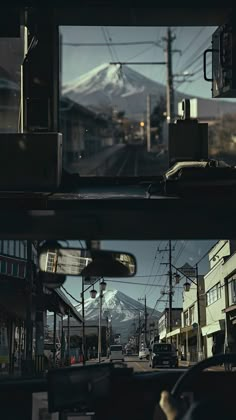 the view from inside a car looking at a mountain in the distance and cars parked on the street