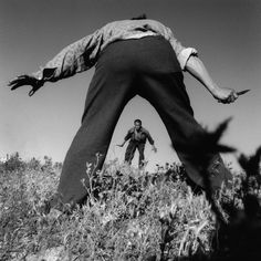 a man is standing in the middle of a field with his arms spread out to grab something