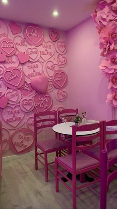 a dining room with pink walls and purple chairs in front of the wall has hearts on it