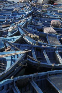 many blue boats are lined up together on the beach