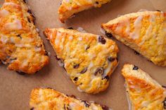 several pieces of scones with icing and raisins sitting on a piece of parchment paper