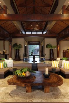 a living room filled with lots of furniture next to a tall wooden table in front of a doorway