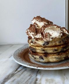 a stack of pancakes topped with whipped cream and chocolate