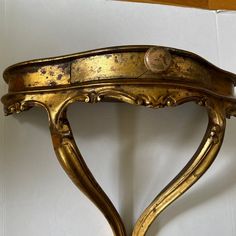 an ornate gold shelf with a button on it's top and two legs, in the shape of a heart