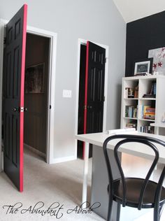 a room with a desk, bookcases and two doors in the wall next to it