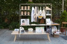 a wooden table topped with pictures and cards next to a wall covered in greenery