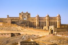 an old castle sits in the middle of a desert area, surrounded by rocks and dirt