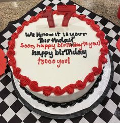 a birthday cake with the number seven on it sitting on a checkered tablecloth