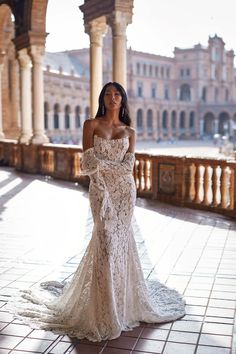 a woman in a white dress standing on a tiled floor next to columns and pillars