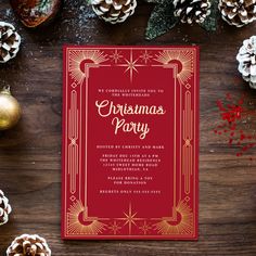 a red and gold christmas party card on top of a wooden table with pine cones