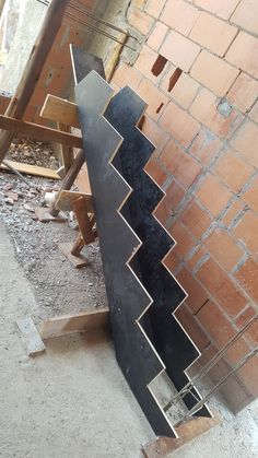 a large metal piece sitting on top of a wooden floor next to a brick wall