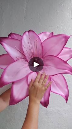 a person holding a large pink flower in their hand