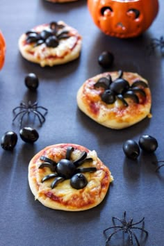 small pizzas decorated with black olives and spider decorations