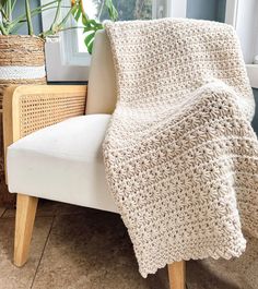 a crocheted blanket sitting on top of a chair next to a potted plant