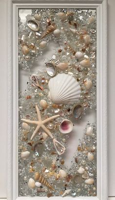 sea shells and starfish are arranged in a white frame on the wall, along with other seashells