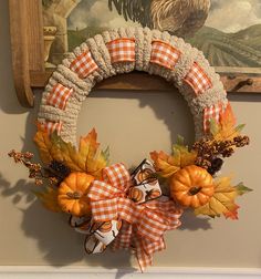 a wreath is hanging on the wall with pumpkins and other autumn decorations around it