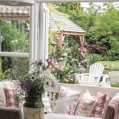 a white couch sitting next to a window filled with lots of flowers and greenery