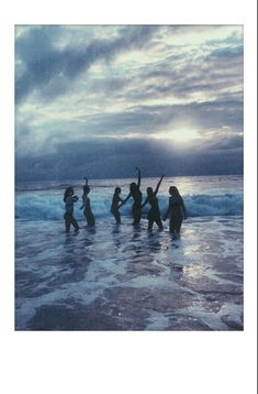 some people are standing in the water and one is holding up a surfboard with their hands