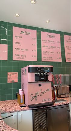 a pink machine sitting on top of a counter next to a green tiled kitchen wall