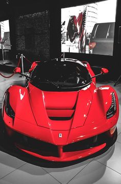 a red sports car on display in a showroom